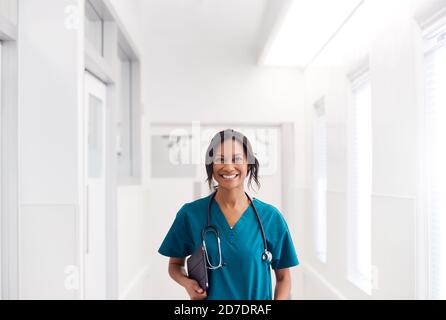 Portrait d'une femme souriante qui porte des exfoliants dans le couloir de l'hôpital Tablette numérique Banque D'Images