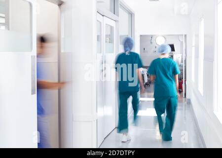 Flou de mouvement du personnel médical portant des exfoliants en plein travail Couloir de l'hôpital Banque D'Images