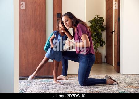 Fille Whispering à mère comme elle quitte la maison pour l'école Banque D'Images