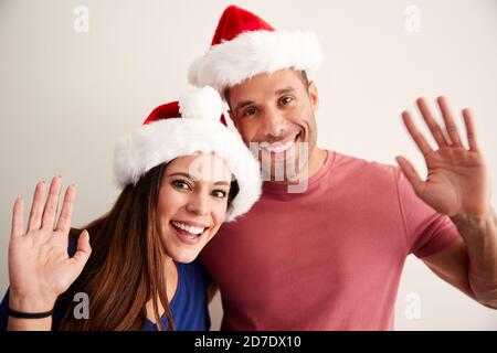 Portrait d'un couple hispanique portant des Santa Hats célébrant les festivités de Noël À la caméra Banque D'Images