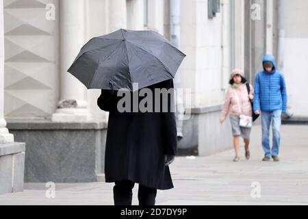 Pluie dans une ville, homme en manteau d'automne avec parapluie noir marchant dans une rue. Les gens dans le temps pluvieux, la saison d'automne Banque D'Images