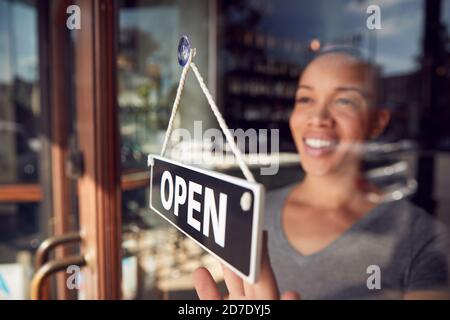 Femme propriétaire d'un café-restaurant ou d'un restaurant tournant Panneau rond ouvert sur la porte Banque D'Images