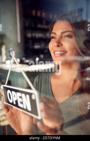 Femme propriétaire d'un café-restaurant ou d'un restaurant tournant Panneau rond ouvert sur la porte Banque D'Images