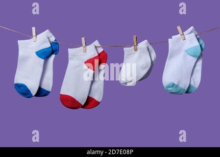 Concept du jour de la prématurité mondiale. Taille normale et petites chaussettes sur corde avec fond violet Banque D'Images