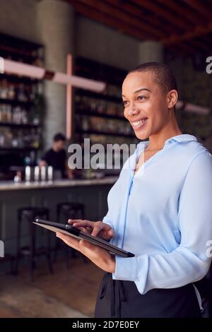 Femme confiante propriétaire du bar-restaurant debout près du comptoir de la tenue Tablette numérique Banque D'Images
