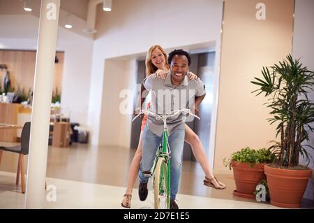 Homme d'affaires et femme d'affaires ayant plaisir vélo d'équitation dans le bureau après Faire du vélo pour travailler Banque D'Images
