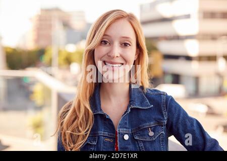 Portrait de jeune femme d'affaires souriante debout à l'extérieur du bâtiment de bureau avec City Skyline derrière Banque D'Images