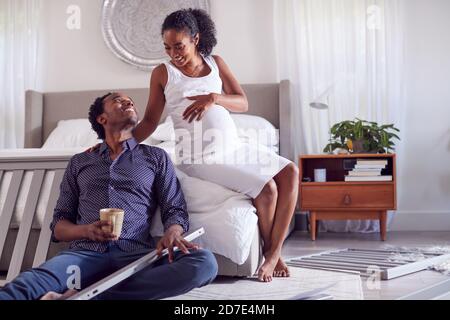 Couple avec femme enceinte en train de mettre ensemble Self Assembly Baby Cot Dans la chambre Banque D'Images