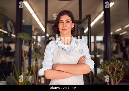 Portrait de la femme souriante propriétaire de Floristes debout à la porte Entouré de plantes Banque D'Images