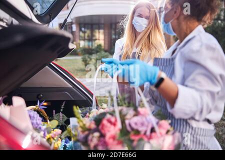 Les ouvriers professionnels de fleuriste emballant des sacs avec des fleurs dans la voiture Banque D'Images