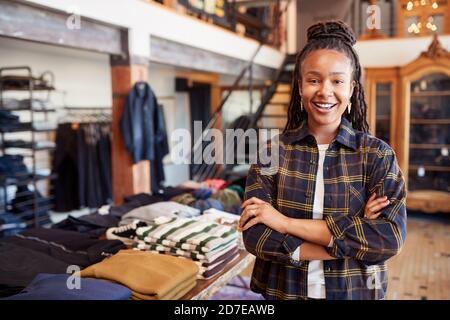 Portrait de la femme souriante propriétaire de magasin de mode debout Avant du présentoir à vêtements Banque D'Images