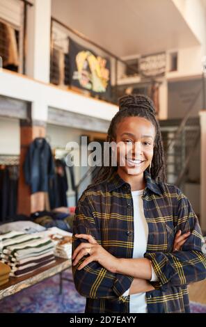 Portrait de la femme souriante propriétaire de magasin de mode debout Avant du présentoir à vêtements Banque D'Images