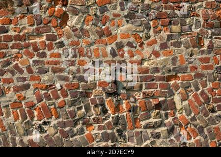 Une section de mur antique de brique rouge avec construction aléatoire Et avec plaque d'ancrage en fer forgé en S. Banque D'Images