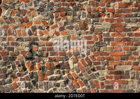 Une section de mur antique de brique rouge avec construction aléatoire Et avec plaque d'ancrage en fer forgé en S. Banque D'Images