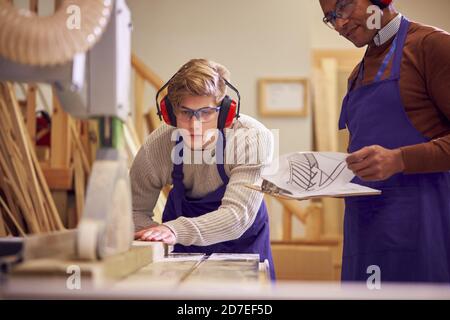 Tuteur avec un étudiant en menuiserie masculine en atelier étudiant pour l'apprentissage À l'université en utilisant la scie à table Banque D'Images