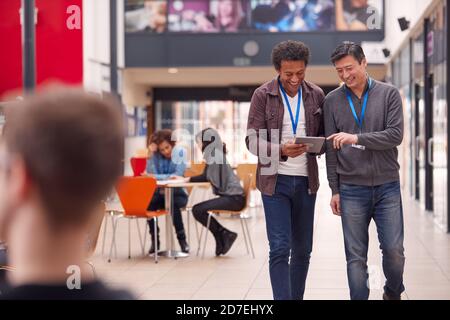 Deux étudiants ou enseignants de sexe masculin avec Digital Tablet Walk Via Hall of College Building Banque D'Images