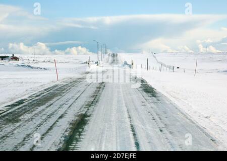 Une route givrée entourée de neige blanche. Fin mars, le printemps est encore loin dans Finmark, un comté du nord de la Norvège. Banque D'Images