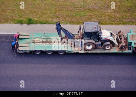 Chargement de la pelle hydraulique sur la plate-forme d'un équipement de construction chariot de transport Banque D'Images
