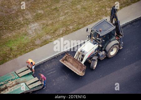 Les travailleurs chargent la pelle hydraulique de construction sur une remorque de camion pour le transport vers un autre emplacement Banque D'Images