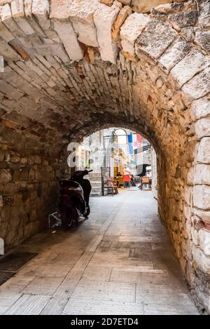 Arche en pierre reliant les vieilles rues médiévales de Trogir, Croatie avec une moto et le drapeau de la Croatie Banque D'Images