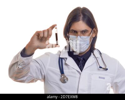 Le médecin en masque de protection et gants isolés sur fond blanc tient le tube à essai contenant un échantillon de sang qui a été testé pour le virus. Concept médical. Banque D'Images