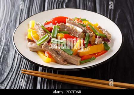 Cuisine chinoise la langue de boeuf avec le poivron, l'oignon et les graines de sésame gros plan dans une assiette sur la table. Horizontale Banque D'Images