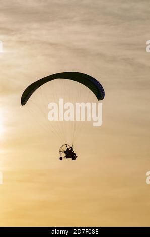 Parapente volant dans le ciel au coucher du soleil Banque D'Images