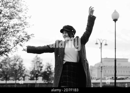 Bonne femme élégante qui se hante dans une rue aux mains éparses. Portrait dynamique noir et blanc en style parisien Banque D'Images