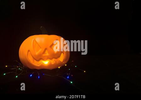 Citrouille d'Halloween jaune effrayante avec une bouche lumineuse, des lumières sur fond noir et un espace de copie. Citrouille illuminant dans l'obscurité Banque D'Images