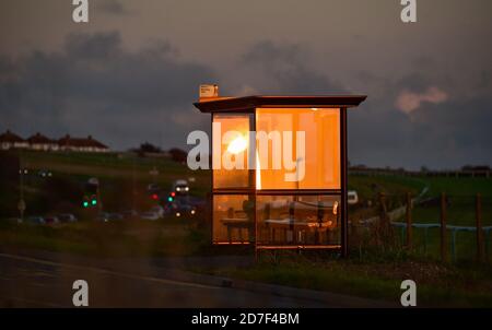 Brighton UK 22 octobre 2020 - le soleil couchant se reflète dans un arrêt de bus par Brighton Racecourse à l'est de la ville, car le temps instable devrait se répandre à travers la Grande-Bretagne au cours des prochains jours : Credit Simon Dack / Alay Live News Banque D'Images