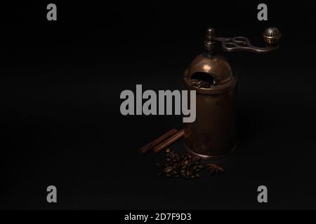 Ancien moulin à café manuel avec haricots, bâtonnets de cannelle, anis aux couleurs sombres. Copier l'espace Banque D'Images