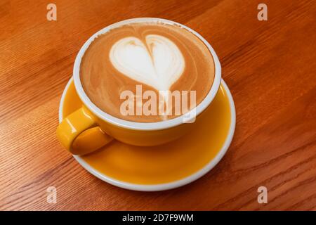 Tasse de café jaune avec latte en forme de coeur Banque D'Images