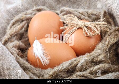 Œufs de poulet dans un panier en osier sur toile. Banque D'Images