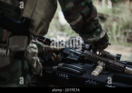 Un militaire avec une affaire d'arme à feu prend un fusil d'assaut dans la ville détruite. Concept d'opération militaire et de sauvetage. Banque D'Images