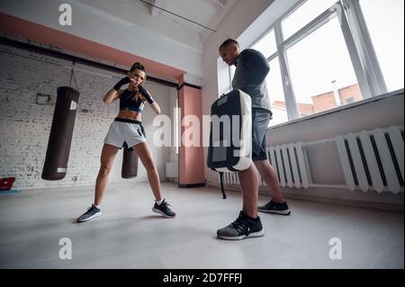 Combat d'entraînement des kickboxers masculins et féminins. Des coups de pied et des coups de pied sur la patte de boxe. Travail par paires Banque D'Images