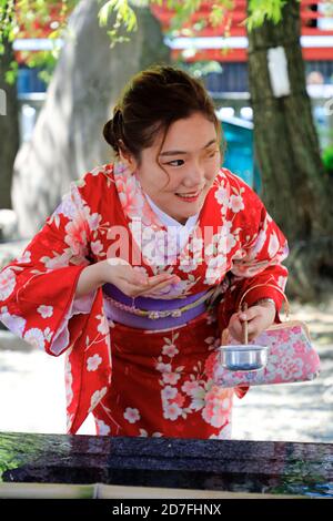 Jeune femme à kimono utilisant la louche d'eau qui obtient de l'eau Fontaine rituelle pour nettoyer les mains avant d'entrer dans le temple Senso-Ji.Asakusa.Tokyo.Japon Banque D'Images