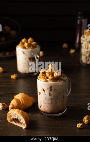 Mugs en verre avec milkshake au chocolat, pop-corn au caramel et chocolat croissants sur fond de bois Banque D'Images