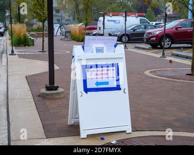 Oak Park, Illinois, États-Unis. 22 octobre 2020. Les premiers électeurs subissent le temps humide et attendent jusqu'à une heure et demie pour voter aujourd'hui à la mairie de village dans cette banlieue ouest de Chicago. Ici, un panneau dirige les électeurs qui ont des bulletins de vote par la poste vers une boîte de dépôt sécurisée. Banque D'Images