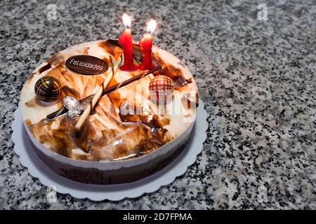 Trois gâteaux au chocolat avec une bougie d'anniversaire avec le numéro 11 et une barre au chocolat avec le texte de joyeux anniversaire en espagnol (felicidades), anniversaire Banque D'Images