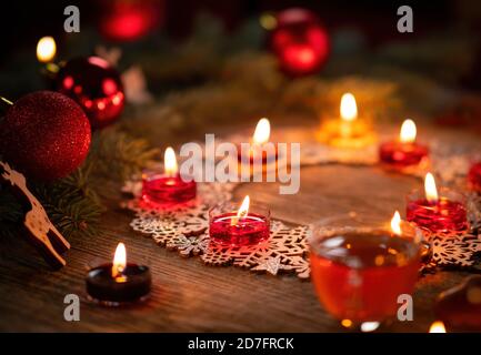 Décoration ornementale d'hiver avec bougies allumées sur table rustique en bois. Punch au vin chaud avec pain d'épice au premier plan. Vacances de Noël et nouveau Banque D'Images