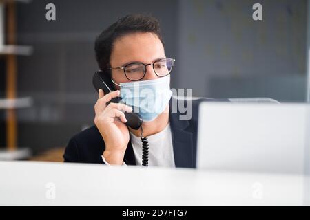 Réceptionniste homme à la réception du bureau portant un masque facial Banque D'Images