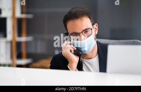 Réceptionniste homme à la réception du bureau portant un masque facial Banque D'Images