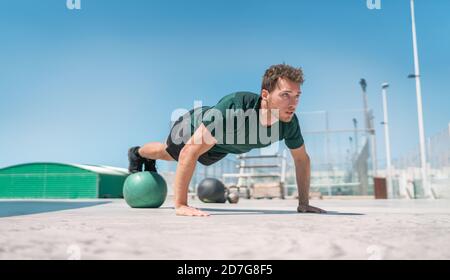 Exercices de forme homme entraînement de force noyau faire l'équilibre push-ups entraînement à la salle de gym extérieure équilibre sur la stabilité medecine ball avec les jambes. Poids corporel Banque D'Images