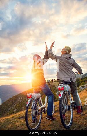 Couple senior actif célébrant le succès sur un beau coucher de soleil. Banque D'Images