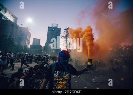 SANTIAGO, CHILI-18 OCTOBRE 2020 - un manifestant célèbre avec une bombe à la fumée orange lors d'une manifestation à Plaza Italia à Santiago, au Chili Banque D'Images