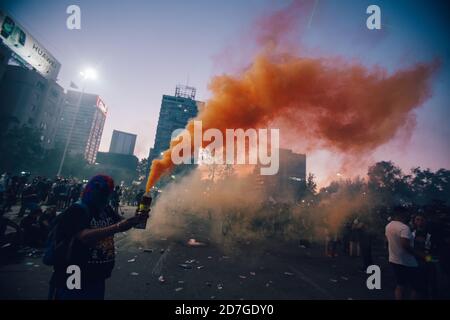 SANTIAGO, CHILI-18 OCTOBRE 2020 - un manifestant célèbre avec une bombe à la fumée orange lors d'une manifestation à Plaza Italia à Santiago, au Chili Banque D'Images