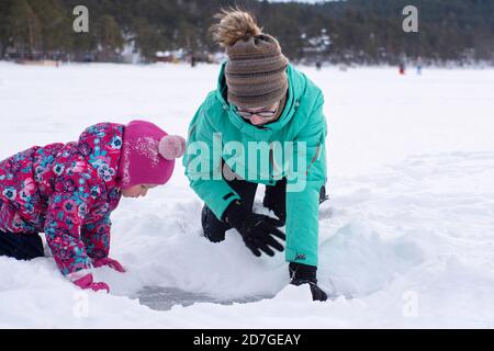 Deux filles sculptent de la neige, les filles poussent la neige de côté pour regarder la glace gelée, les jeux d'hiver à l'extérieur, l'espace de copie. Banque D'Images