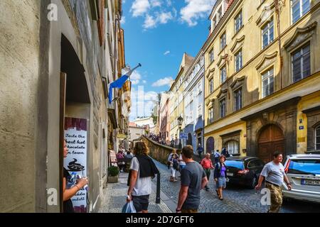 Une petite rue latérale reliant l'escalier au complexe du château de Prague avec une jeune dame à la porte d'un café tandis que les touristes se promeuneront. Banque D'Images