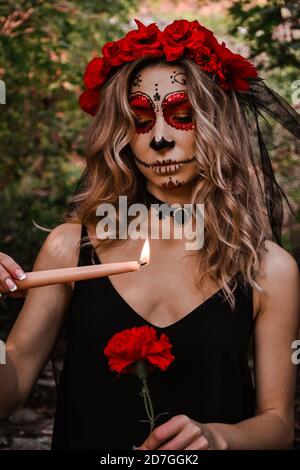 Joyeux Halloween concept. Effrayée femme horrible dans une tenue spéciale, porte le crâne d'argile blanche, sucre professionnel maquillage de crâne pour paraître effrayant, porte noir Banque D'Images