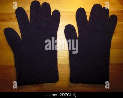 Une paire de gants d'hiver en laine bleue sur une table la nuit Banque D'Images